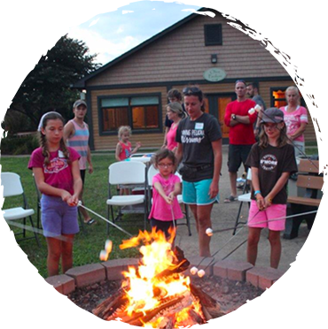 families enjoying roasting marshmallows at a campfire